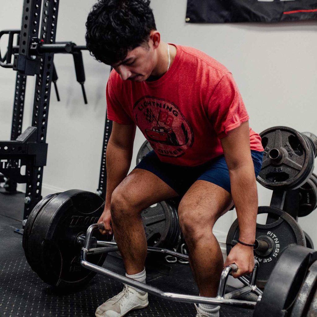 young male athlete lifting weights in a gym